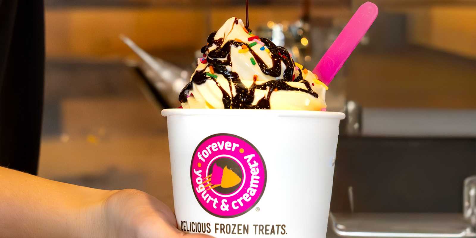 Chocolate syrup being added to a cup of yogurt