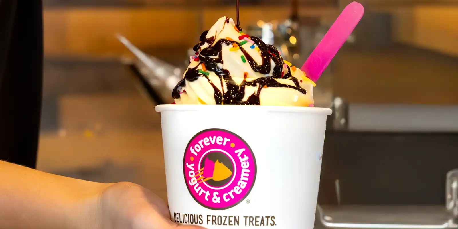 Chocolate syrup being added to a cup of yogurt